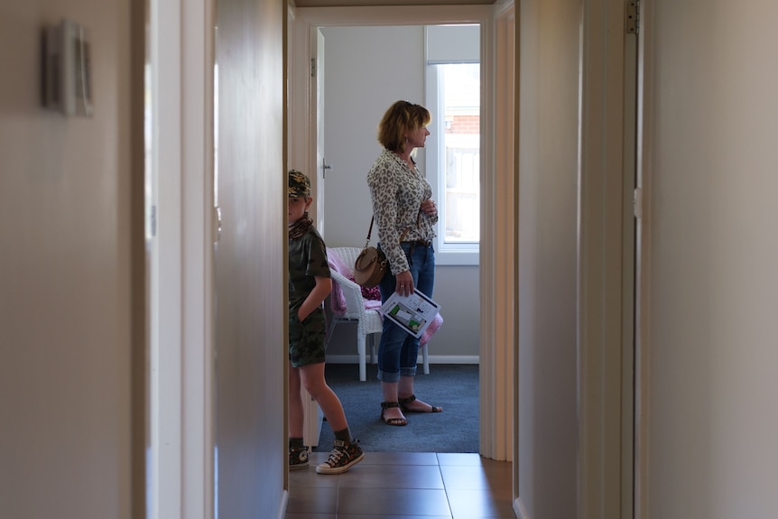 A woman looks through a backroom as a young boy steps into an adjacent room.