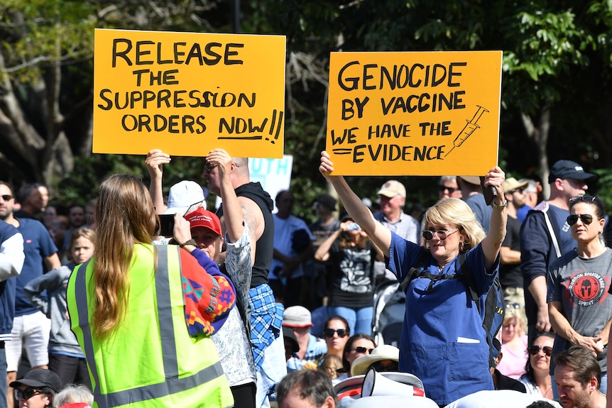Protesters during an anti-lockdown protest in Brisbane last weekend. Both hold signs with anti-vaccination messaging. 