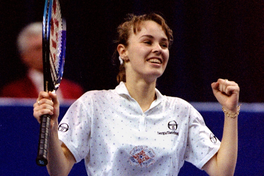 Young Martina Hingis raises her hands in triumph.