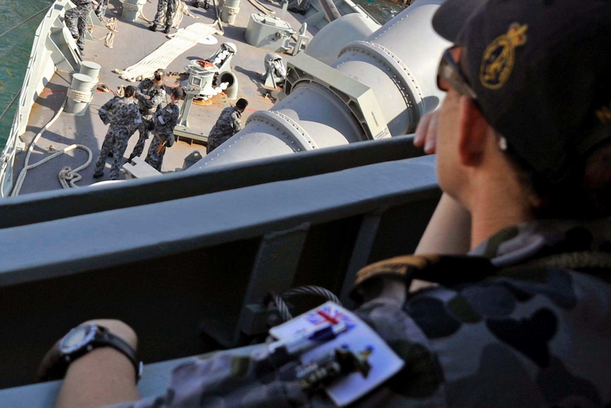 An Australian Navy Lieutenant watches proceedings on board an Australian navy ship.