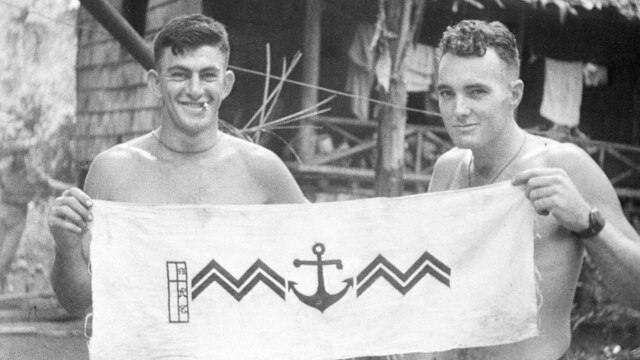 Australian soldiers holding a Japanese emblem captured during the Milne Bay fighting, 1942-10-01.