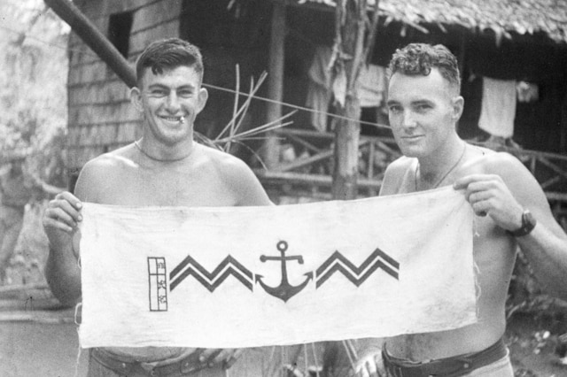 Australian soldiers holding a Japanese emblem captured during the Milne Bay fighting, 1942-10-01.