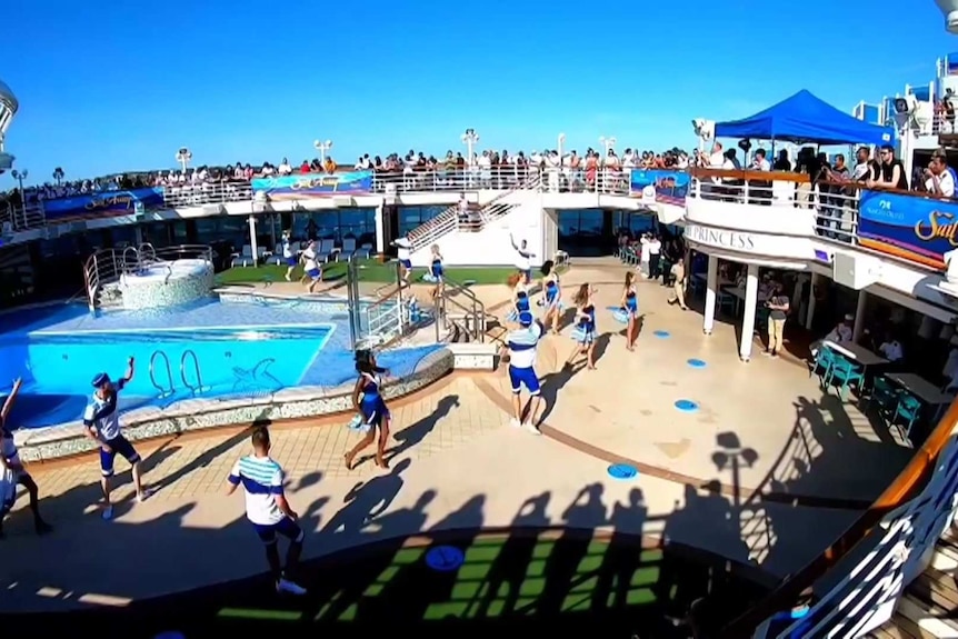 People dance around a swimming pool as others watch on.