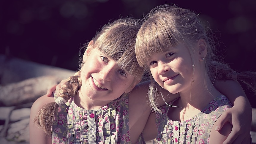 Two girls smile and have their arm around each other