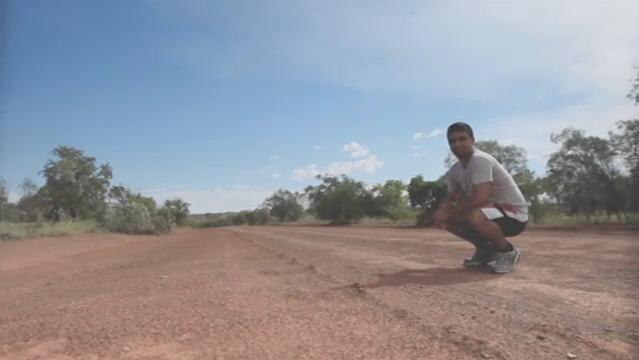 A man crouches down on an outback road
