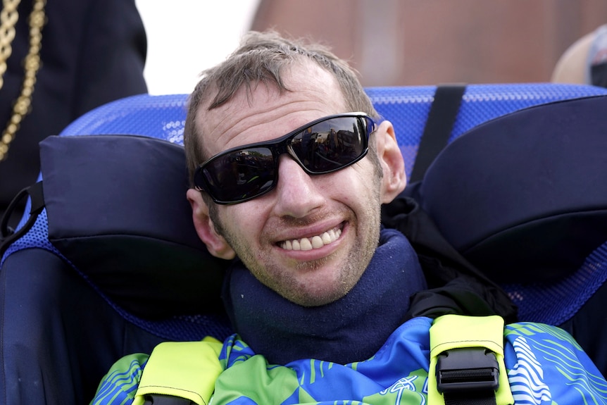 Man wearing sunglasses sits in a wheelchair. 
