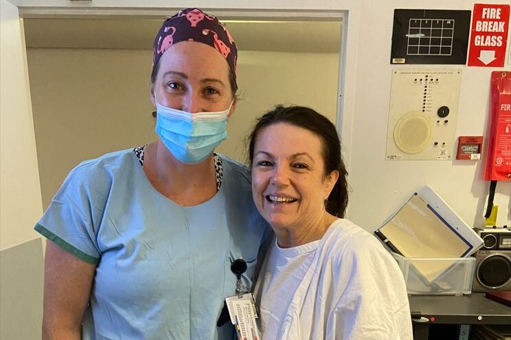 Two women in hospital gowns smile.