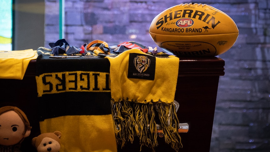 Coffin with Richmond Tigers scarf on top and yellow football