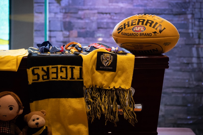 Coffin with Richmond Tigers scarf on top and yellow football