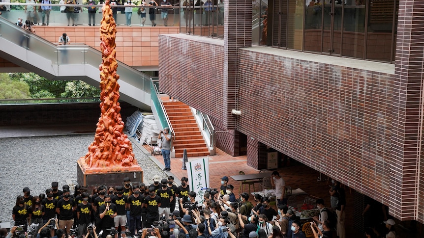 University students observe a minute of silence in front of the Pillar of Shame statue at the University of Hong Kong.