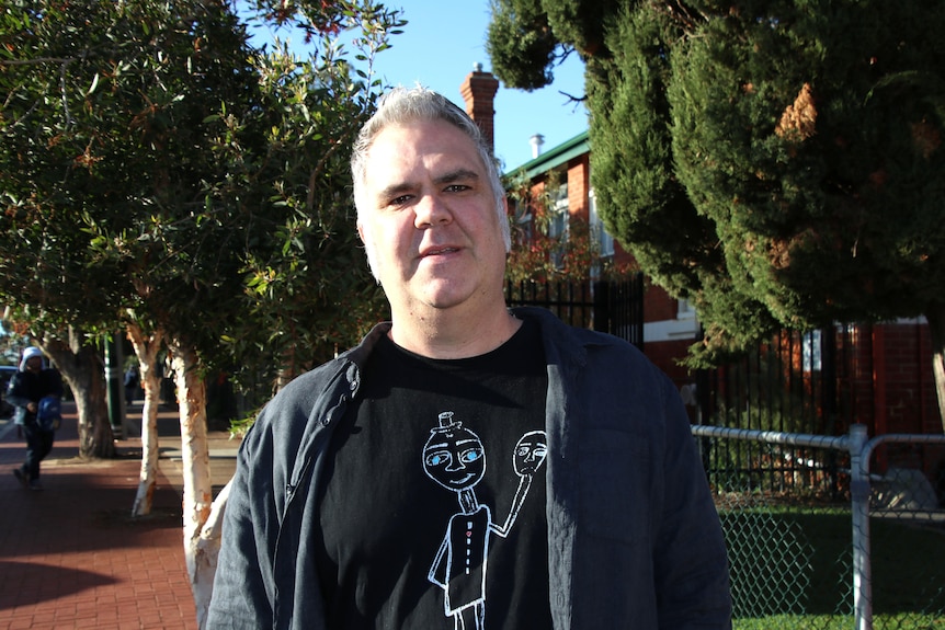 A man stands in front of a school