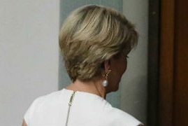 Dressed in white, Julie Bishop leaves through the doors of the House in Canberra.