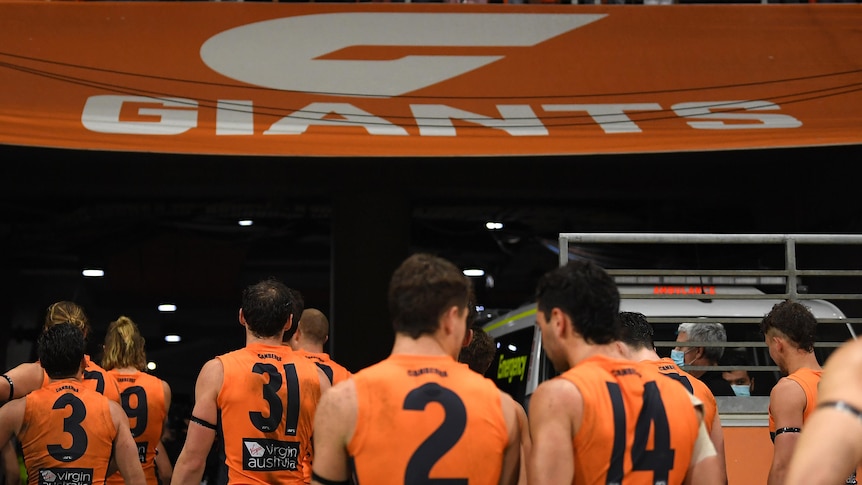 GWS Giants AFL players walk from the field as they are cheered by their supporters.