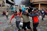 A wounded protester is carried to receive first aid during clashes with security forces on Rasheed Street in Baghdad