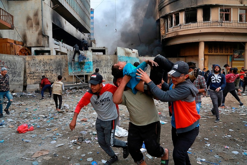 A wounded protester is carried to receive first aid during clashes with security forces on Rasheed Street in Baghdad