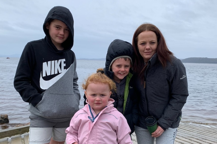 Three children and their mother stand on a wharf