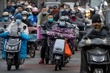 Traffic on motorbikes, riders wear face masks. 