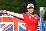 Minjee Lee, draped in the Australian flag, holds a trophy