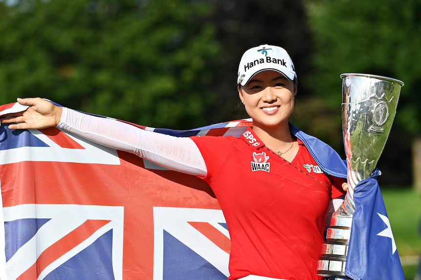 Minjee Lee, draped in the Australian flag, holds a trophy
