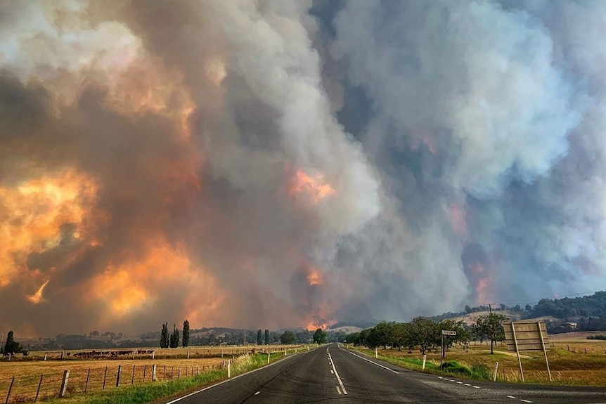 A red sky shrouded in thick smoke over a a highway.