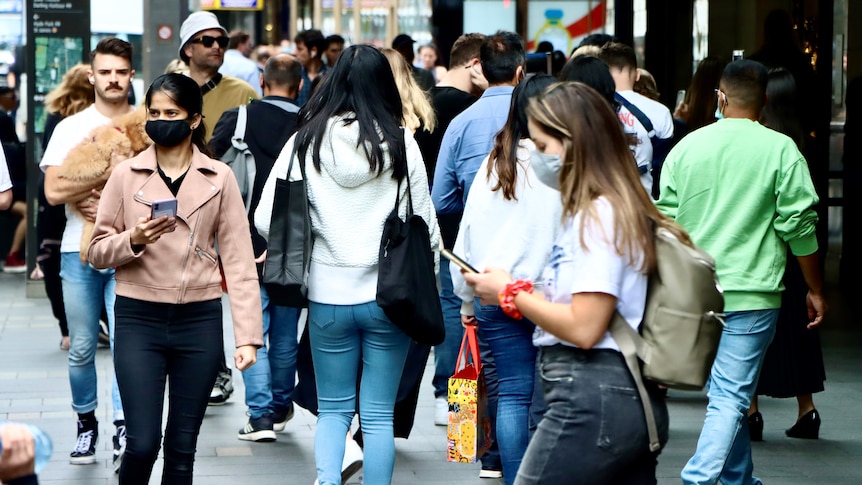 Crowd of shoppers in Sydney's Pitt St Mall, some wearing masks, post-lockdown during COVID pandemic.