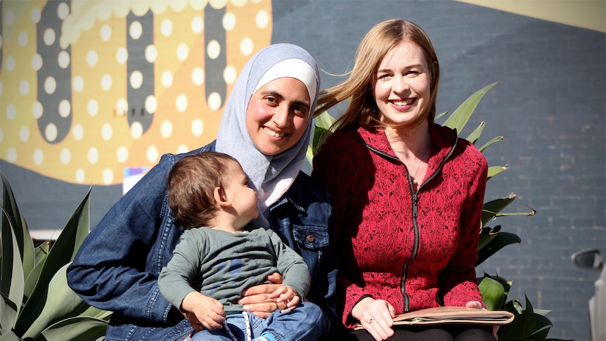 Wafaa Izz Eddin and holds son Ammar while sitting next to Emily Glenn.