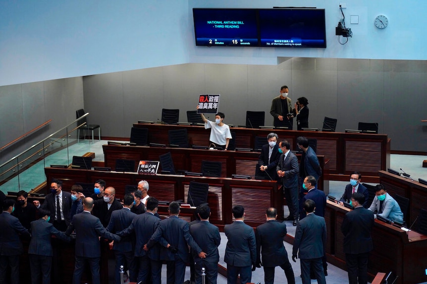 Pro-democracy MP Tanya Chan, centre, holds a placard reading "A murderous regime stinks for ten thousand years" in Hong Kong's Legislative Council chamber