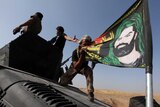 A member of the Iraqi Special Operations Forces (ISOF) kisses a shiite flag on the top of a military vehicle on the outskirts of Bartila, east of Mosul, during an operation to attack Islamic State militants in Mosul