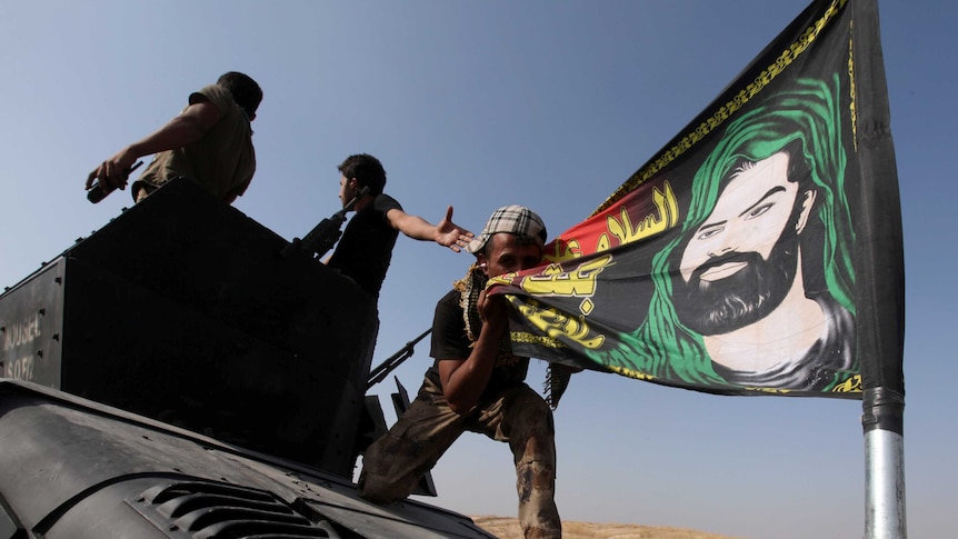 A member of the Iraqi Special Operations Forces (ISOF) kisses a shiite flag on the top of a military vehicle on the outskirts of Bartila, east of Mosul, during an operation to attack Islamic State militants in Mosul