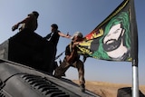 A member of the Iraqi Special Operations Forces (ISOF) kisses a shiite flag on the top of a military vehicle on the outskirts of Bartila, east of Mosul, during an operation to attack Islamic State militants in Mosul