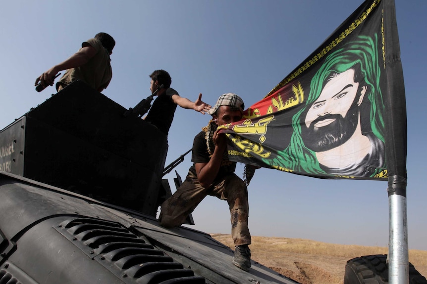 A member of the Iraqi Special Operations Forces (ISOF) kisses a Shiite flag.