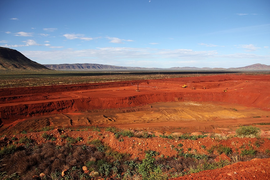 A wide shot of a mining development along red dirt plains.