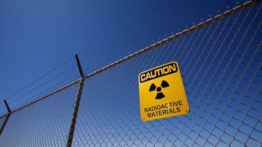 A sign on a fence saying caution radioactive materials