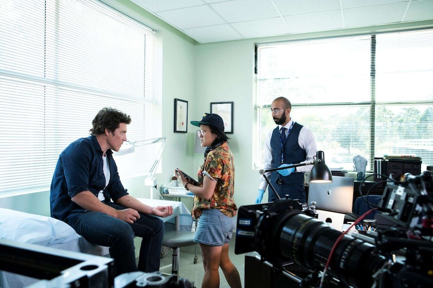 Director Corrie Chen on a film set with two actors on either side of her, big camera in the foreground