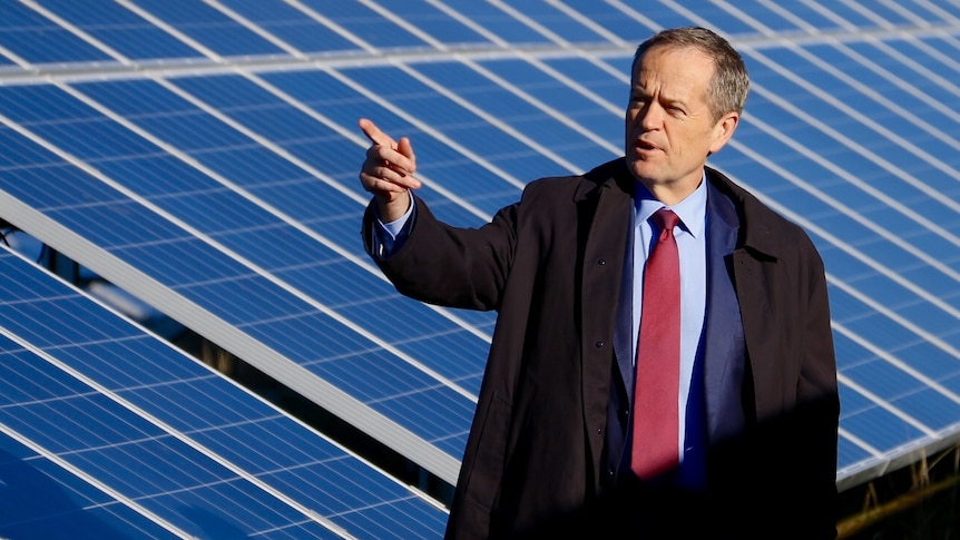 Bill Shorten stands in front of solar panels.