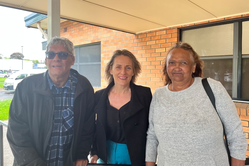 Two women and a man smiling.