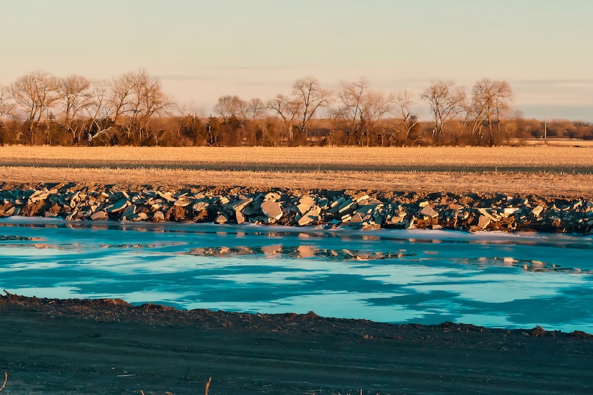 An icy canal with a field beyond.