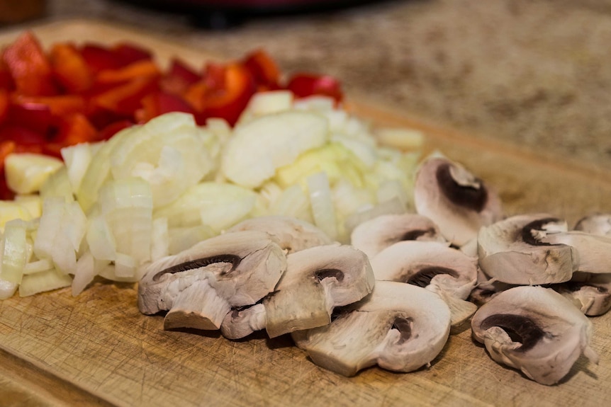 Chopped mushroom, onion and capsicum on a wooden board
