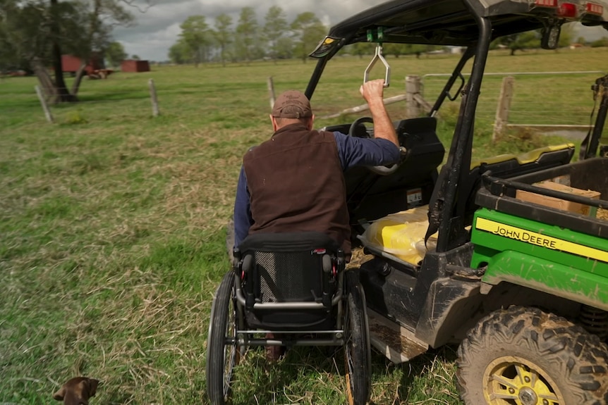 Photo of a man in a wheelchair next to a tractor.
