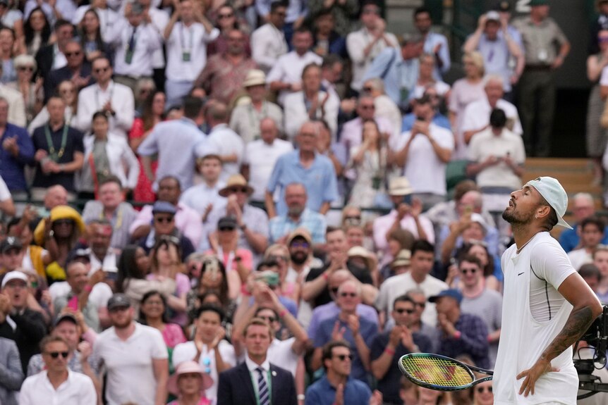 Nick Kyrgios tilts his head up to the sky with his hands on hips, as a large crowd watches