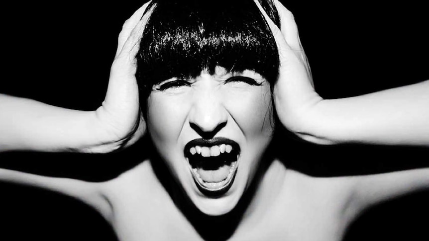 A woman holds her her head and screams.