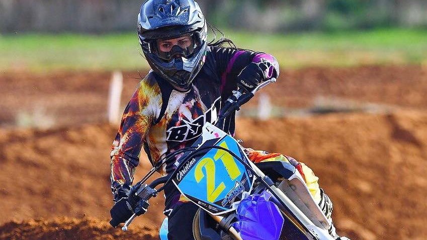 A female motocross rider going around a bend.