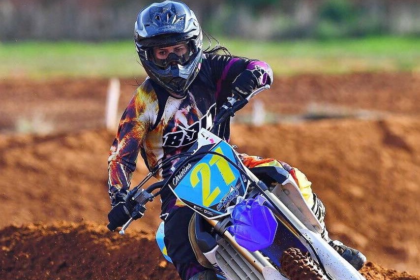 A female motocross rider going around a bend.