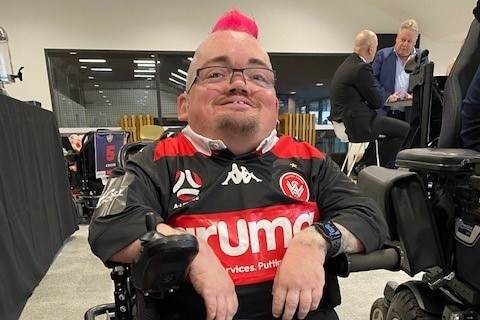 Gardien de football australien en fauteuil roulant Andy Waite balançant son mohawk rose. 