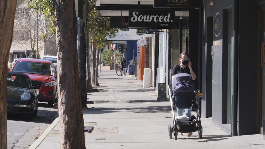 Empty streets with a woman wearing a mask pushing a pram