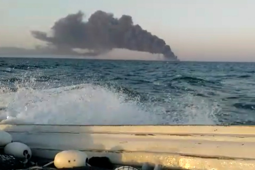 Fumul care se ridica dintr-o navă navală iraniană a ieșit peste orizont, preluat de pe o barcă mică.