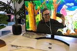 Kim appears on a computer screen with painted galahs behind her