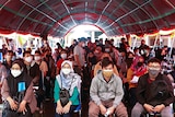 People wearing protective face masks sit before receiving a dose of the coronavirus disease (COVID-19).