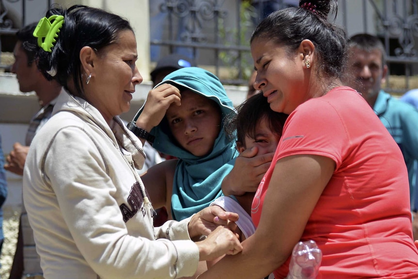 Relatives of victims mourn outside the cemetery