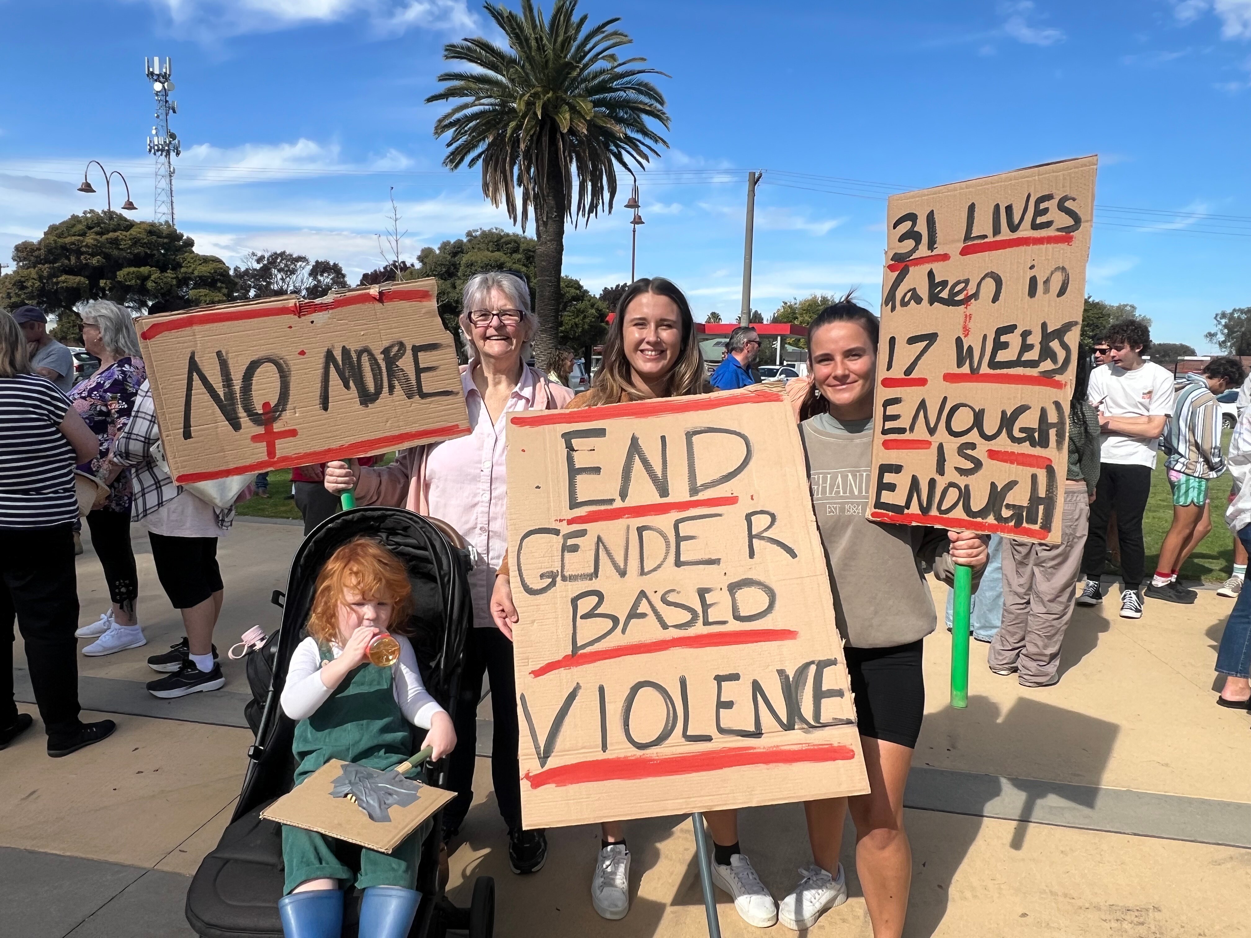 Three women holding up signs protesting violence against women